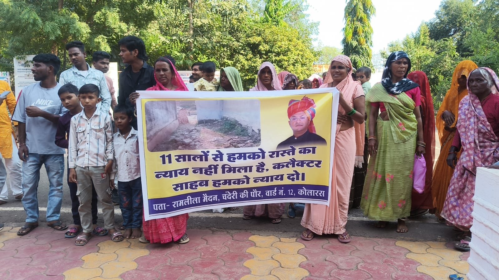 कलेक्टर अर्पित वर्मा की तस्वीर के साथ बैनर पर लिखा “11 सालों से हमको रास्ते का न्याय नहीं मिला, कलेक्टर साहब हमको न्याय दो” / Shivpuri News